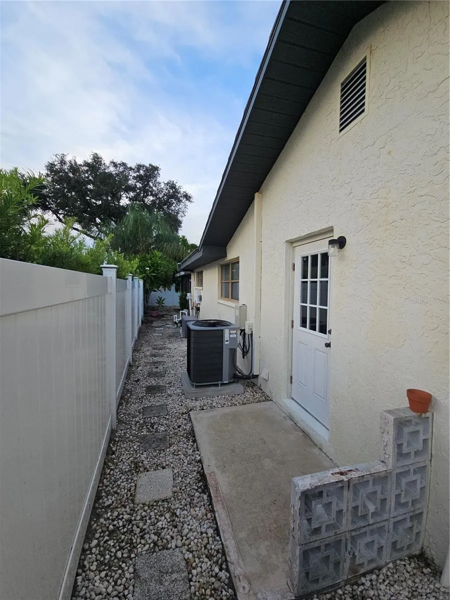 West Side of Home with door to laundry, AC, NEW Pool Pump and door to screened in pool.