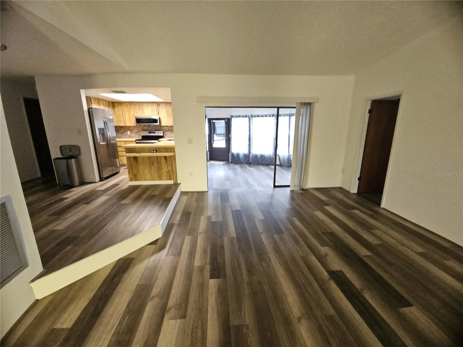 View of Living Room and Sunroom overlooking pool with Kitchen and Dining Room up one step to the left