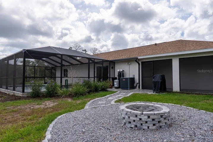 back of house with screened lanai, firepit and walkway to pool