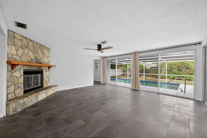 Family room with wood burning fire place and pool view
