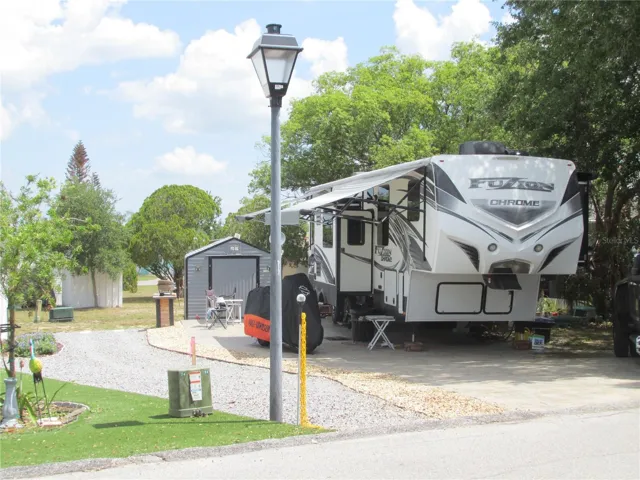 Shaded RV lot with pavered parking pad.