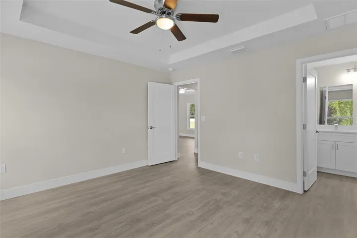 Primary bedroom with tray ceiling and ceiling fan