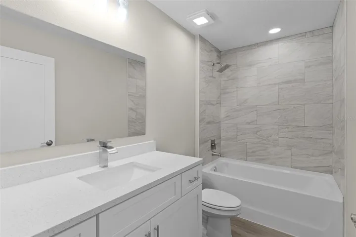 Guest bathroom with quartz countertop and ceramic-tiled tub surround