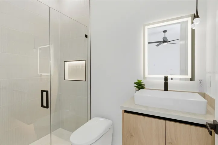 Modern secondary primary bath featuring a glass-enclosed walk-in shower, sleek vanity with vessel sink, LED mirror, and stylish contemporary finishes throughout