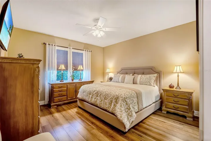 Primary bedroom with ceiling fan and laminate floors