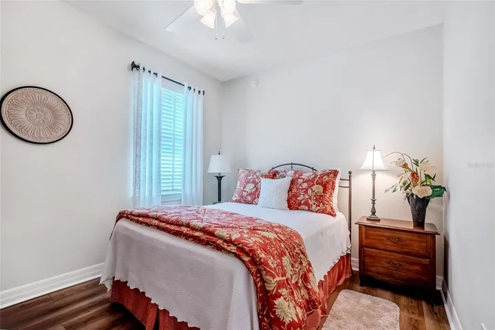 Guest bedroom with ceiling fan and laminate floor.