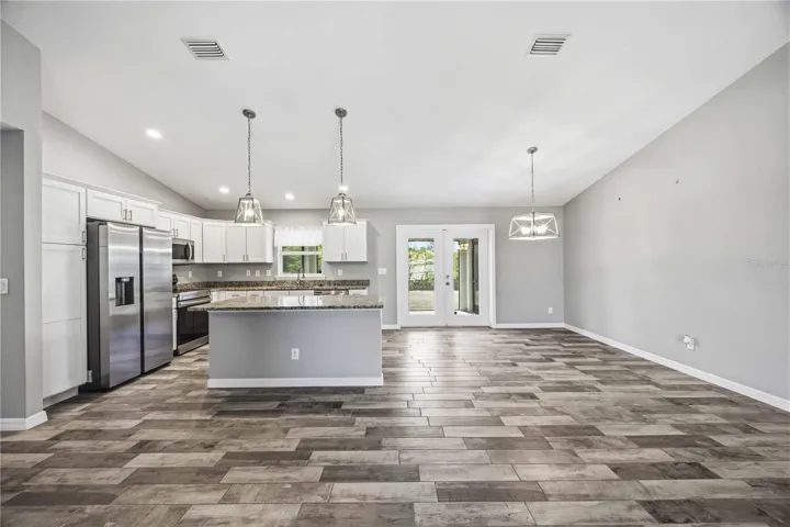 Kitchen features white shaker cabinetry, granite counters and stainless appliances