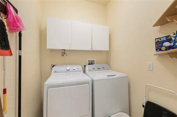 Laundry room has newer washer/dryer, cabinets & shelving