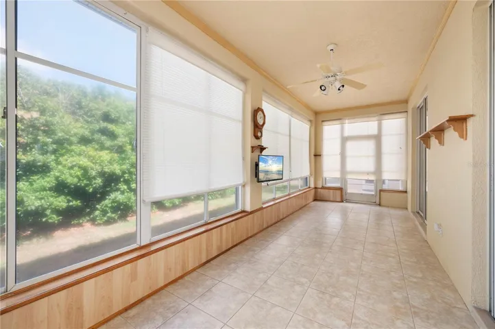 The tiled lanai has ceiling fans, blinds