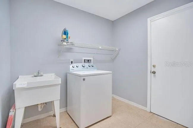 Laundry room equipped with washer and utility sink.