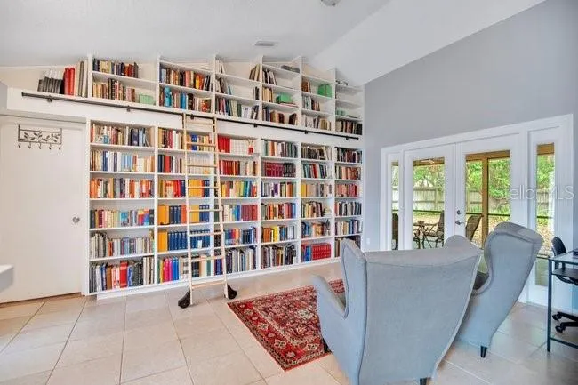 Light-filled living room with custom built-ins and French doors that seamlessly connect to the lanai.