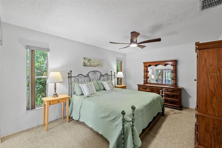 Large Primary bedroom with peaceful backyard views and new ceiling fan.