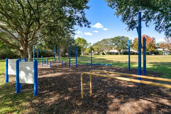 Outdoor fitness/play area shaded by mature trees.