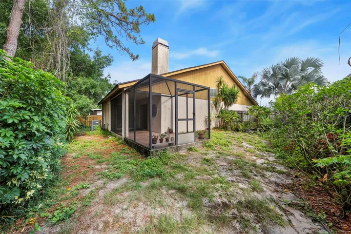 Rear exterior view with screened patio and mature landscaping.