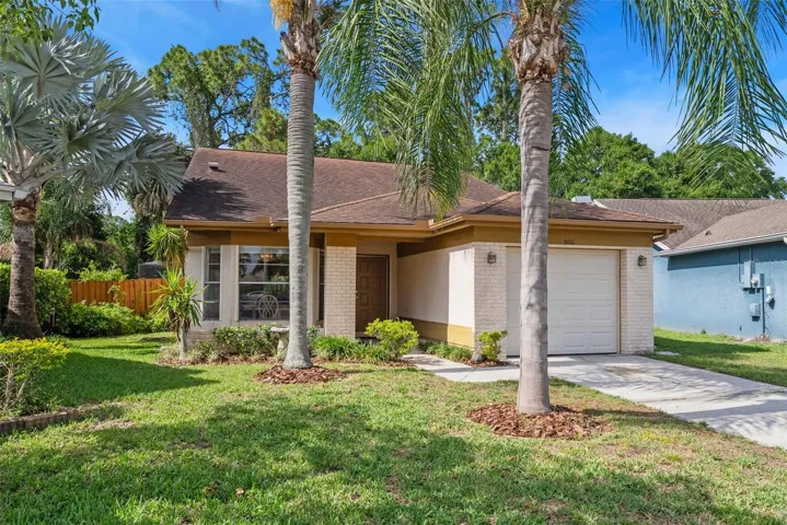 Charming curb appeal with mature palms, lush landscaping, and a welcoming front entry.