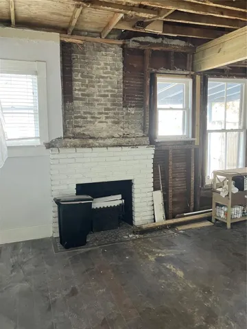 Windows flank charming brick fireplace capped and fitted with electric insert for atmosphere.