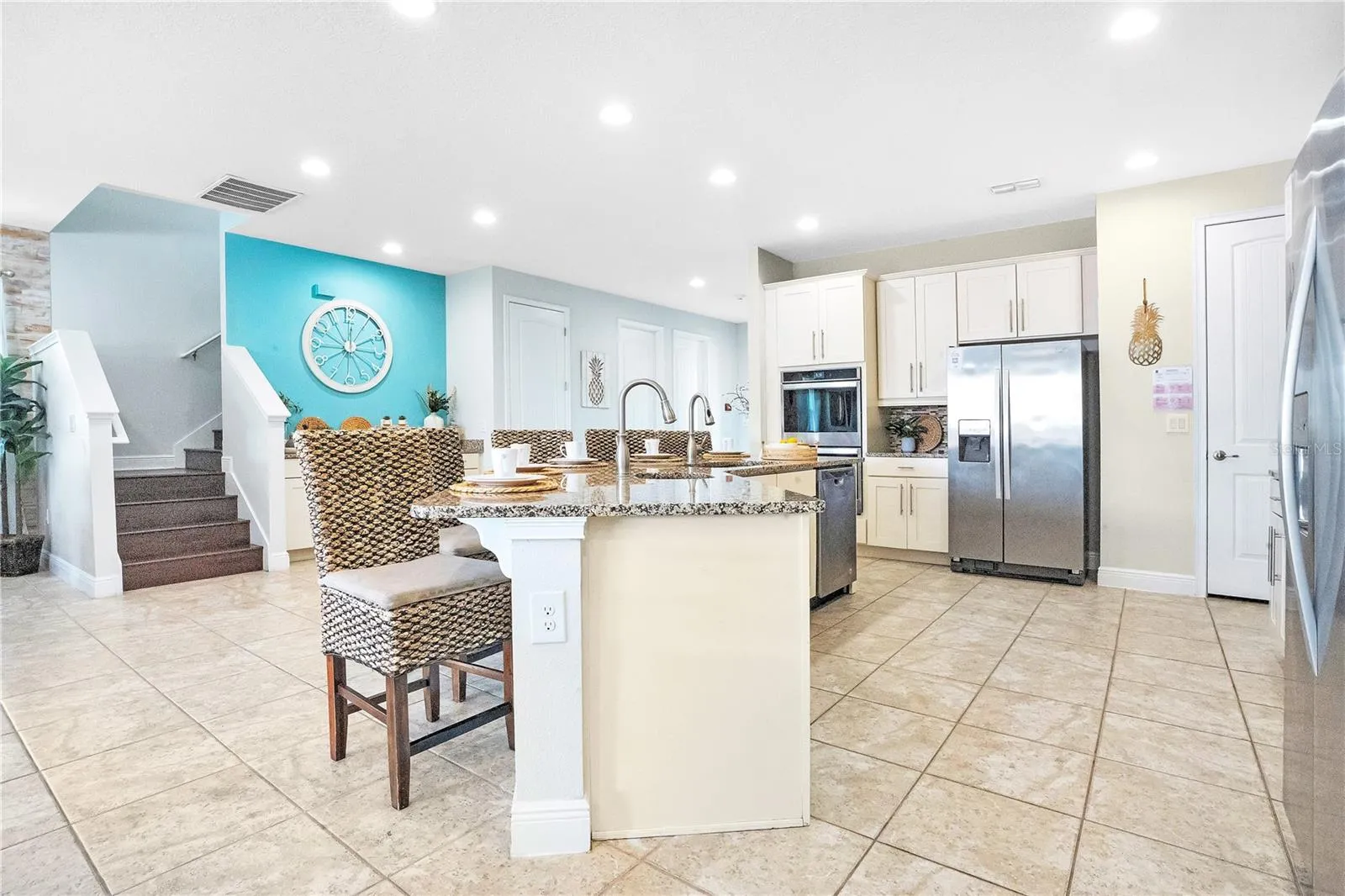 Beautifully designed kitchen with 42-inch white shaker cabinetry, stainless steel appliances, breakfast bar seating for eight, and an open layout that flows seamlessly into the living areas