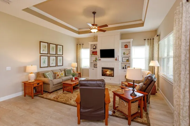 Gathering Room with Custom Built-In Shelving, Cabinetry, and Electric Fireplace. Thoughtfully designed hidden storage is located on both sides of the fireplace and TV. Beautiful tile plank flooring enhances the space throughout.