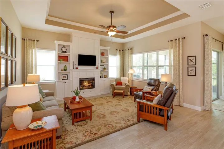 Gathering Room with Custom Built-In Shelving, Cabinetry and Electric Fireplace. Thoughtfully designed hidden storage is located on both sides of the fireplace and TV. Beautiful tile plank flooring enhances the space throughout.