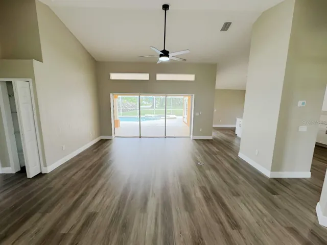 LIVING ROOM WITH TRIPLE SLIDER TOT HE LANAI AND POOL AREA