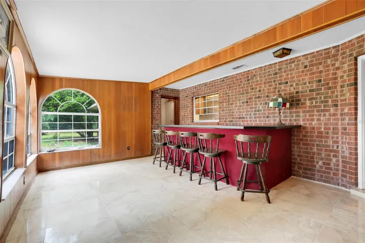 Designed for gathering and entertaining, this versatile space features a built-in bar, kitchen pass-through window, and adjoining half bath.