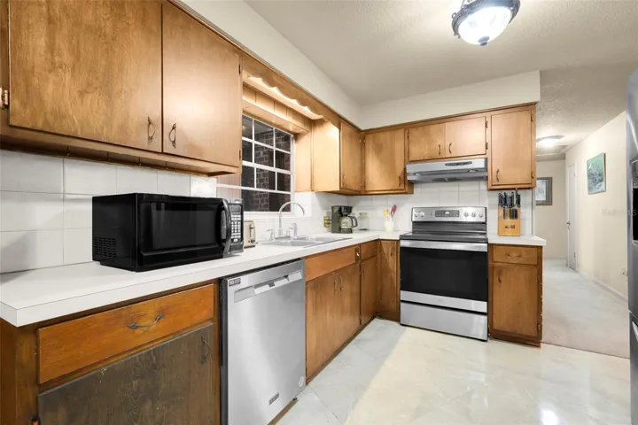 Kitchen with stainless steel appliances and pass-through window connecting to the adjoining flex space.