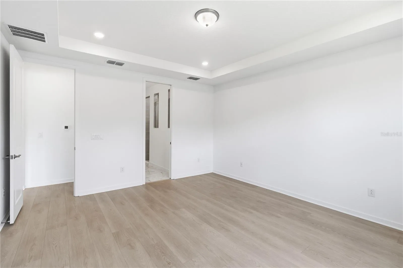 Spacious bedroom with warm flooring, bright walls, and flexible furniture options.