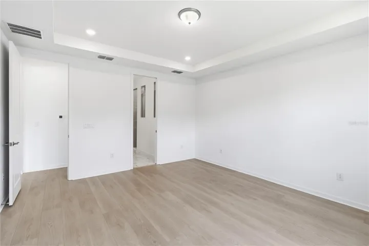 Spacious bedroom with warm flooring, bright walls, and flexible furniture options.