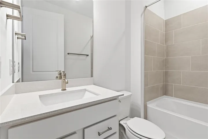Fresh bathroom with upgraded finishes, bright cabinetry, and a tub/ shower.