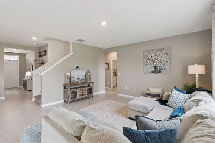 View of the family room from the back of the house. Nice open floor plan providing views of the front foyer, staircase and hallway leading to the guest bedroom and bathroom.