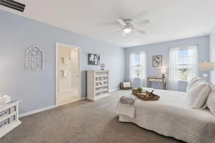 View of owners bedroom and bathroom highlighting the natural light from the front windows and ceiling fan