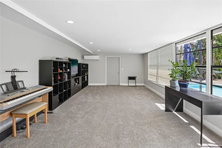 Bonus Room by Pool - This spacious bonus room offers a bright, flexible layout with plush carpeting, recessed lighting, and a wall of windows overlooking the pool area. It’s an ideal space for a media room, game room, fitness area, or additional lounge space.