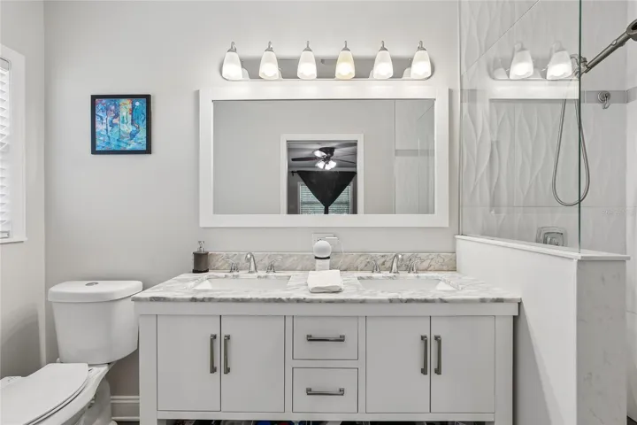 Primary En Suite Bathroom – The primary en suite bathroom features a dual-sink vanity with a marble-look countertop, updated cabinetry, and a wide framed mirror with bright vanity lighting. Clean finishes and a neutral palette give the space a fresh, polished feel.