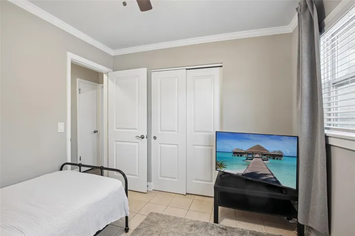 Bedroom Two Closet View – This secondary bedroom includes a double-door closet, neutral wall color, and a mix of tile and carpeted flooring. The window brings in natural light while maintaining a simple, functional layout.