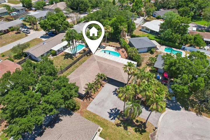 Aerial Property View – This aerial view showcases the home’s setting on a residential street, with the backyard pool, surrounding fencing, and mature trees visible from above. The overview highlights the property’s spacious outdoor layout and connection between the home and pool area.