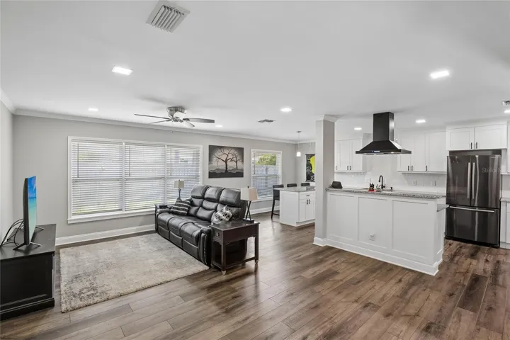 Open Living Area & Kitchen – This open-concept living space flows seamlessly into the updated kitchen, featuring wide-plank wood-look flooring, recessed lighting, and a bright, neutral palette. Large windows bring in natural light across the main gathering area.
