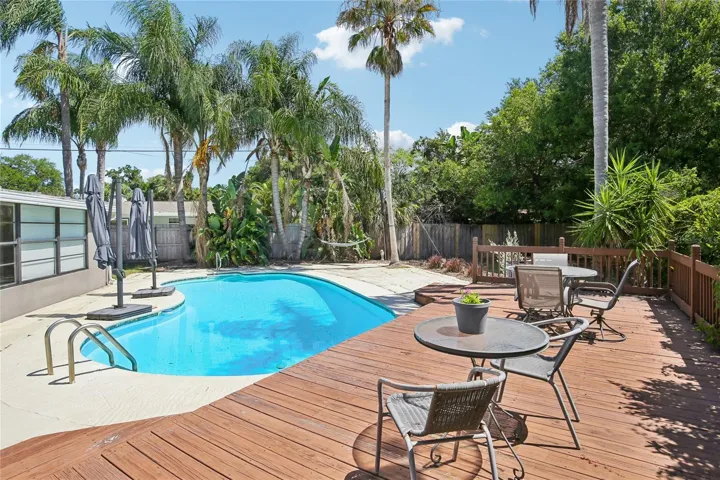 Poolside Entertaining Area – The wood deck overlooks the pool and offers a comfortable setting for outdoor dining or lounging. Lush greenery and privacy fencing create a peaceful backyard backdrop.
