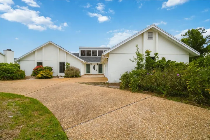 Front exterior with mature landscaping and wide driveway