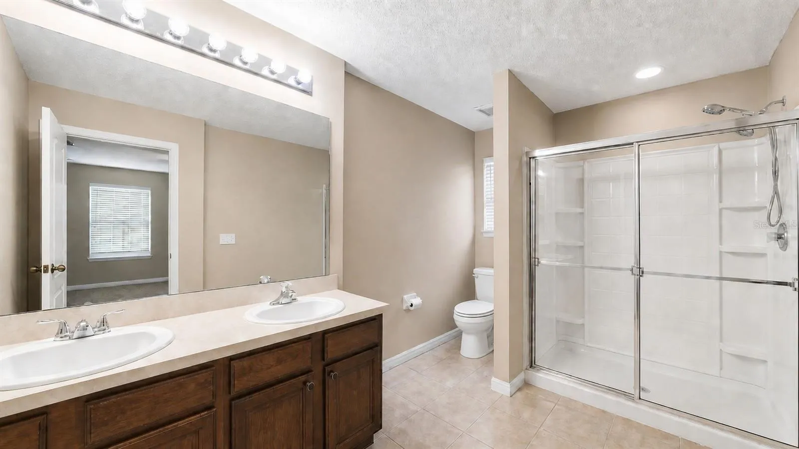 Walk-in shower and dual vanities in the primary bathroom