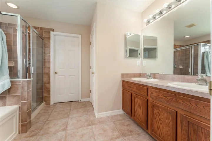 primary bath with dual sinks, soaking tub, separate shower stall, water &amp; linen closets