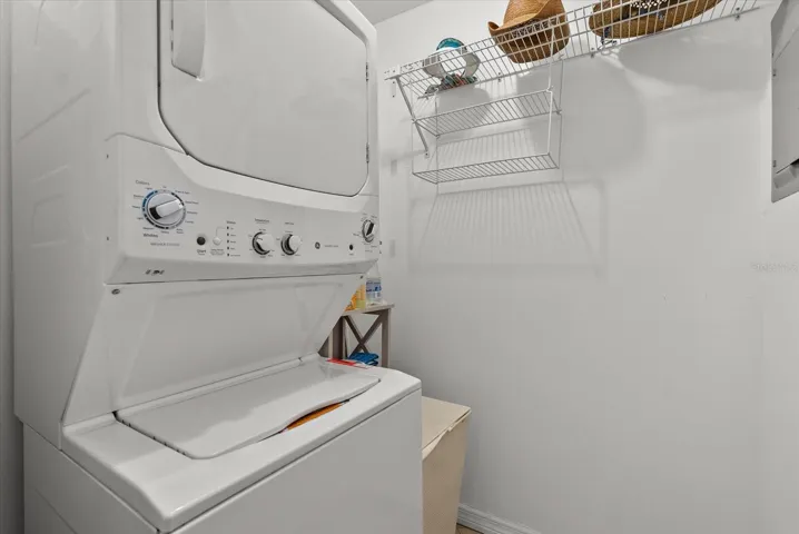 Indoor laundry room with a new stacked washer & dryer.