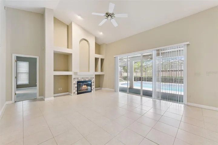 Family Room with wood burning fireplace and view of pool and entry in to primary bedroom