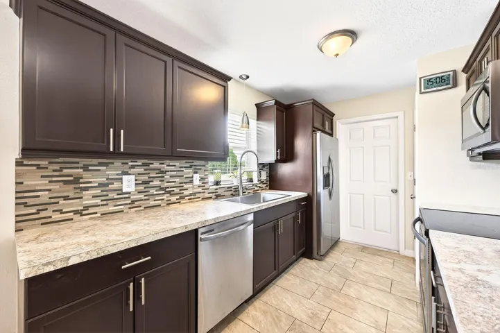 The Kitchen features abundant cabinetry, quartz countertops, stainless steel appliances, a closet pantry, and a NEW SINK, NEW FAUCET, and NEW DISPOSAL added in 2025, combining style and functionality for everyday living.