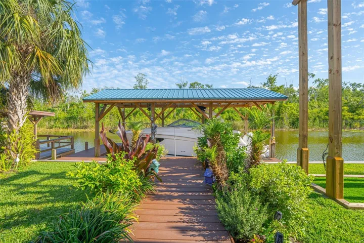 Escape to your own private waterfront oasis featuring a covered boat house with boat lift