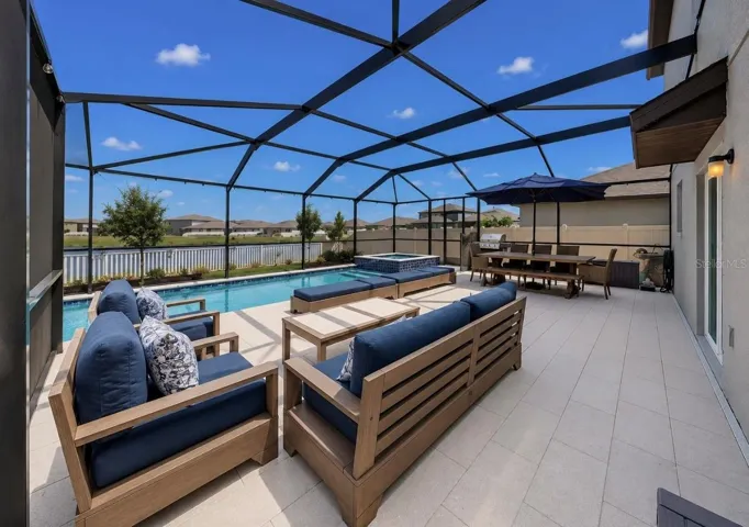 Backyard oasis featuring an enclosed heated saltwater pool and spa, expansive decking, and tranquil pond views