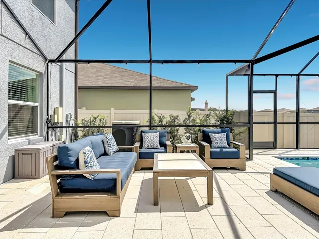 Backyard oasis featuring an enclosed heated saltwater pool and spa, expansive paver decking, and tranquil pond views