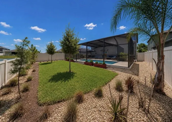 Backyard oasis featuring an enclosed heated saltwater pool and spa, expansive decking, and tranquil pond views