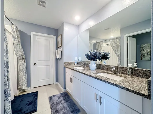 Primary en-suite bathroom with dual sink vanity and step-in shower