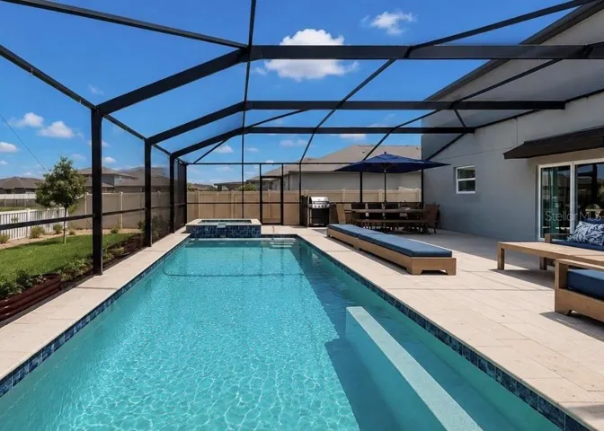 Backyard oasis featuring an enclosed heated saltwater pool and spa, expansive decking, and tranquil pond views