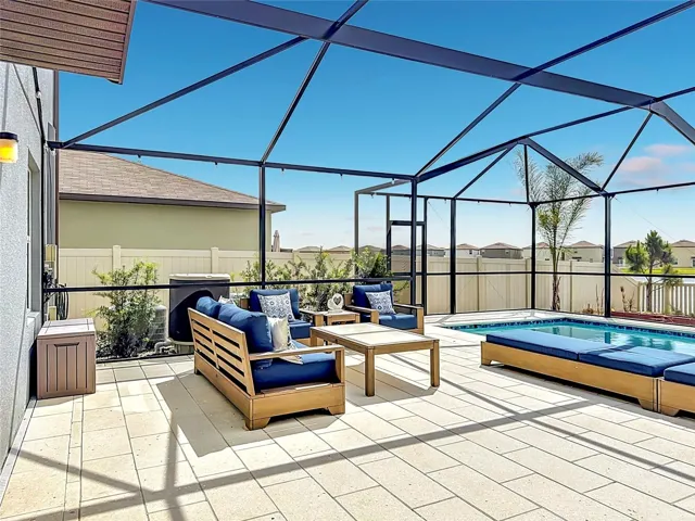 Backyard oasis featuring an enclosed heated saltwater pool and spa, expansive paver decking, and tranquil pond views